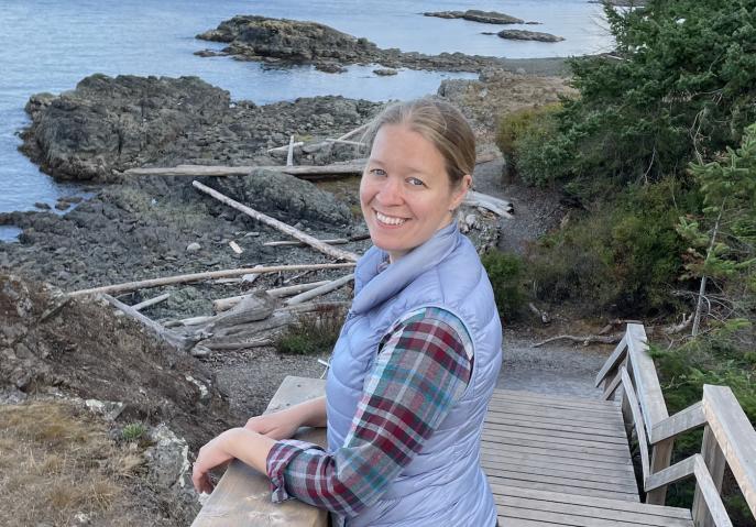 Karin standing on stairs with their hands on the railing