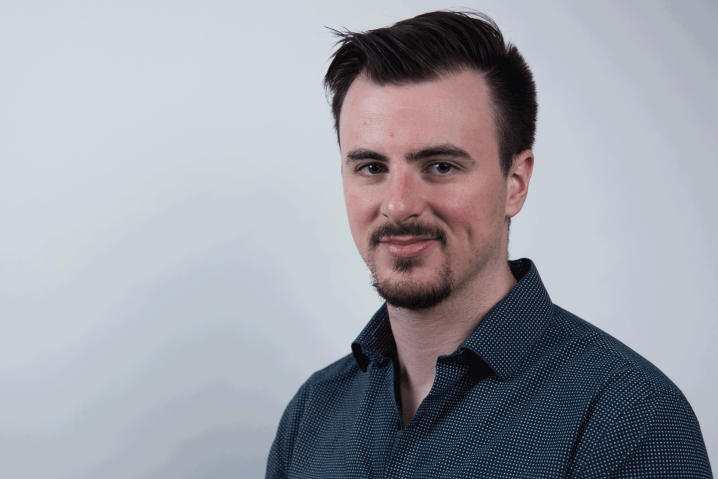 Man with dark hair and goatee, wearing a blue button up shirt