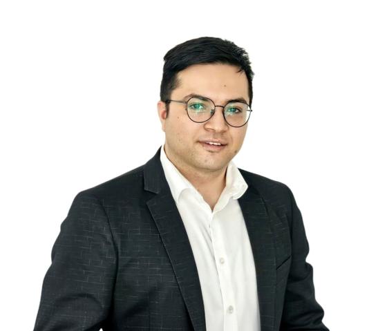 Man with glasses and dark coat with white shirt smiling