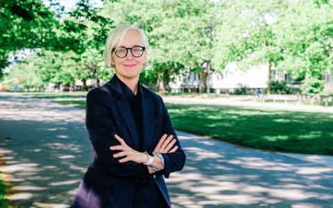 White woman with black shirt standing outside near trees