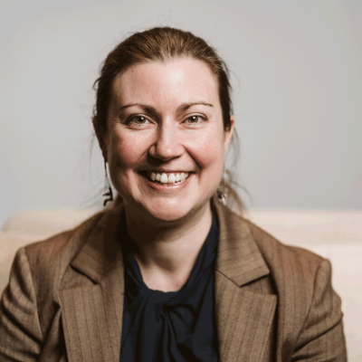 Woman smiling with brown jacket and brown hair